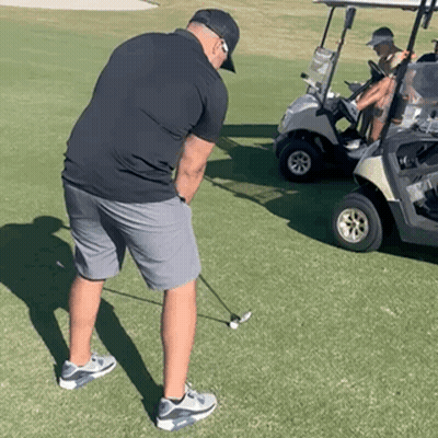 Man Swinging Golf Club Beside Golf Cart GIF