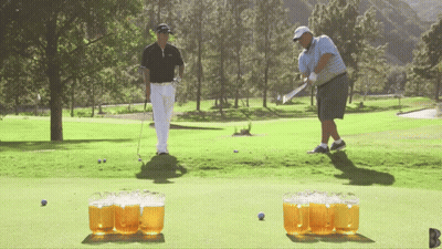 Man Swinging Golf Club While Another Watches GIF