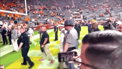 Man Taking Picture Of Police Officer On Football Field GIF