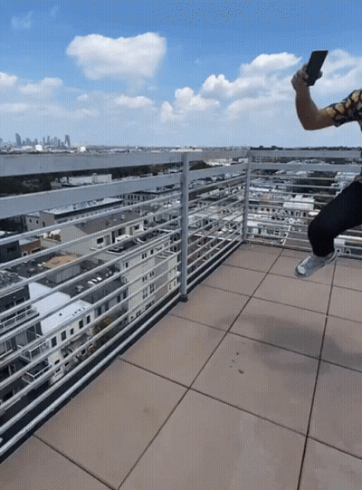 Man Taking Selfie On Balcony With City Background GIF