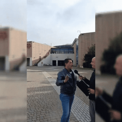 Man Talking Into Microphone In Front Of Building With PP GIF