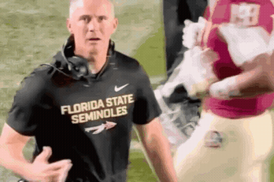 Man Talking Into Microphone In Front Of Farm Bureau Sign GIF