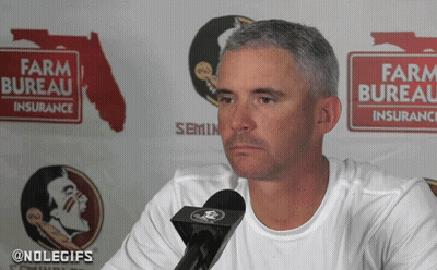 Man Talking Into Microphone In Front Of Farm Bureau Sign GIF