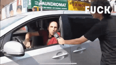 Man Talking Into Microphone In Front Of Laundromat Sign GIF