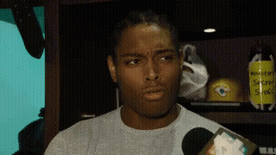 Man Talking Into Microphone In Locker Room With Secret Stuff Sign GIF
