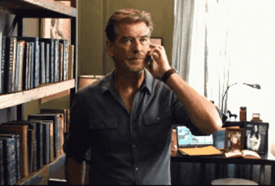 Man Talking On Cell Phone In Front Of Bookshelf With A Brief History GIF