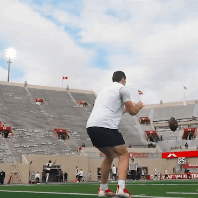 Man Throwing Football In Front Of Stadium With Tomorrow Sign GIF