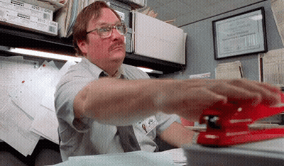 Man Using Stapler In Office Cubicle With Framed Certificate Saying The Office Supply Company GIF
