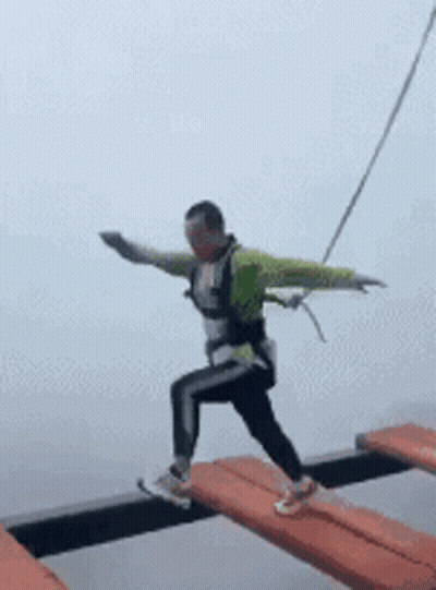 Man Walking Across Bridge With Arms Outstretched GIF