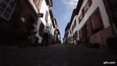 Man Walking Cobblestone Street With Gifs.com Sign GIF