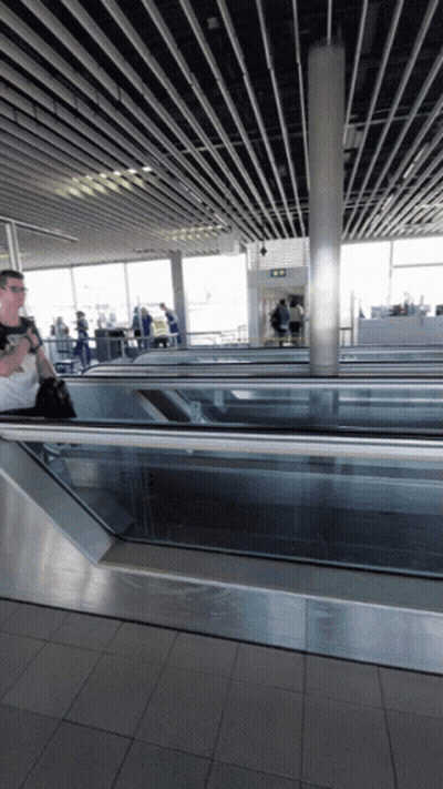 Man Walking Down Escalator With Exit Sign GIF