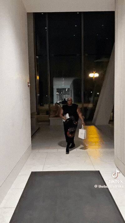 Man Walking Down Hallway With Shopping Bag and Purse