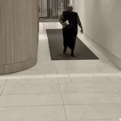 Man Walking Down Hallway With Water Bottle