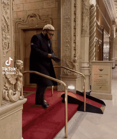 Man Walking Down Stairs With Guest Elevators Sign GIF