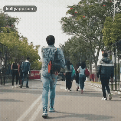 Man Walking Down Street With Group Behind Him GIF