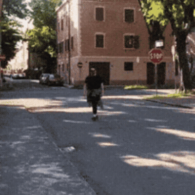 Man Walking Down Street With Stop Sign GIF