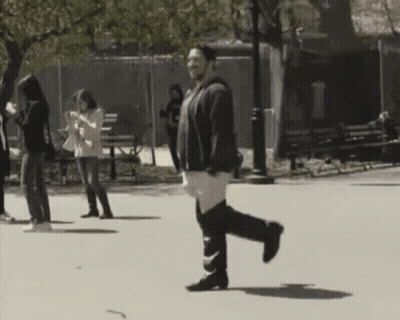Man Walking In Park Looking At Phone GIF