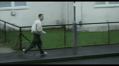 Man Walking On Sidewalk Next To Building GIF