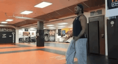 Man Walking Through Gym In Hat GIF