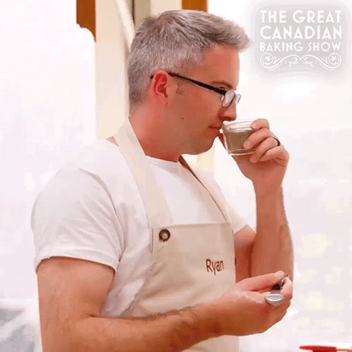 Man Wearing Apron That Says Ryan Drinking From Cup GIF