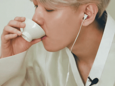 Man Wearing Earbuds Drinking From Small White Cup GIF