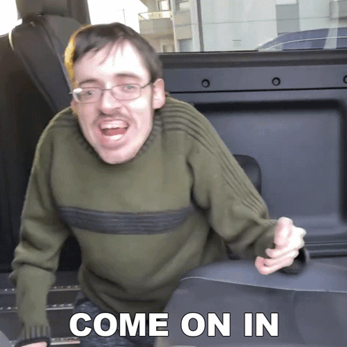 Man Wearing Glasses And Green Sweater Says Come On In Sitting In Back Seat Of Car GIF