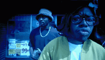 Man Wearing Glasses Stands In Front Of 99 Cents Sign GIF
