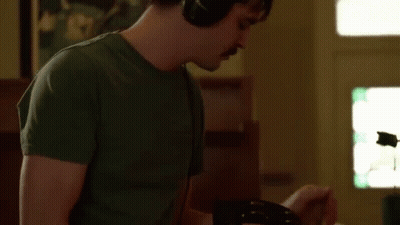 Man Wearing Headphones Playing Guitar In Living Room GIF