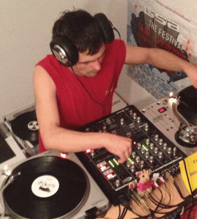 Man Wearing Headphones Playing Record in Front of USB Festival Poster