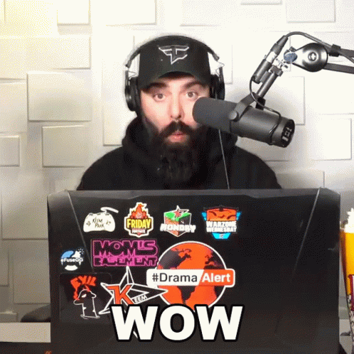 Man Wearing Headphones Stands In Front Of Laptop With Stickers Saying Wow GIF