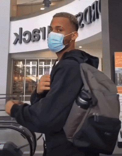 Man Wearing Mask And Backpack Riding Escalator GIF