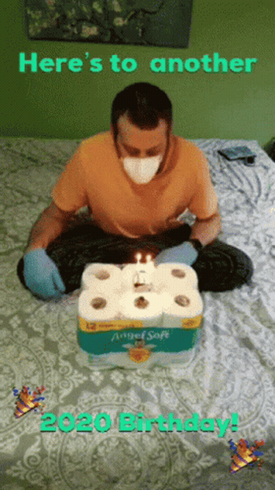 Man Wearing Mask Sitting On Bed With Toilet Paper Cake GIF