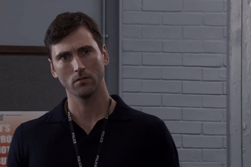 Man Wearing Police Lanyard Looks At Camera GIF