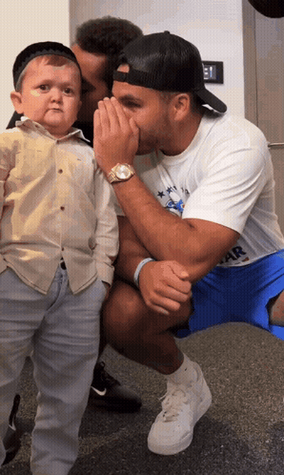 Man Whispering Into Another Man's Ear Wearing Star Shirt GIF