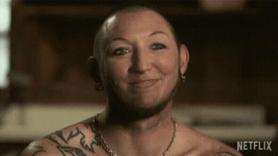 Man With Arm Tattoo Smiling In Front Of Netflix Sign GIF