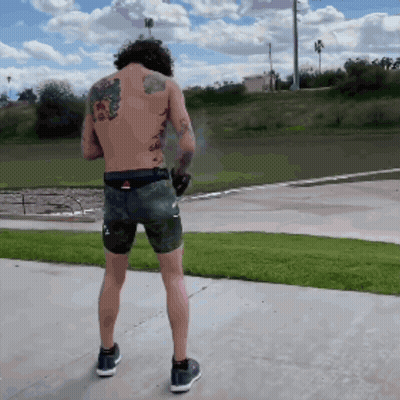 Man With Back Tattoo Standing On Sidewalk GIF