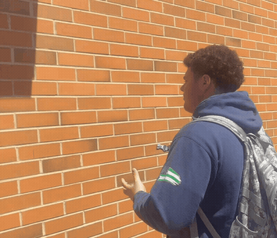 Man With Backpack By Brick Wall GIF