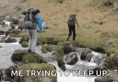 Man With Backpack Crossing River While Another Stands On Rock GIF