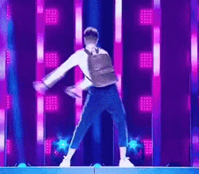 Man With Backpack Dancing On Stage With Purple Lights GIF