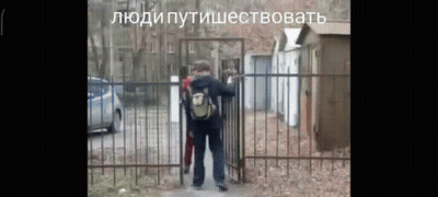 Man With Backpack in Front of Fence With Russian Writing