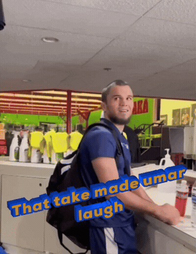 Man With Backpack In Front Of Green Sign Saying Aka GIF