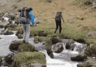 Man With Backpack Walking Across River GIF