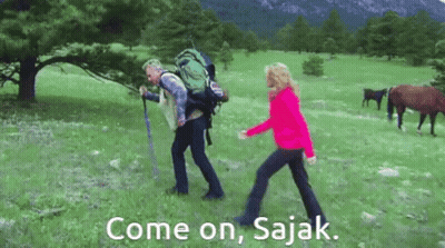 Man With Backpack Walking With Woman In Field With Horses GIF