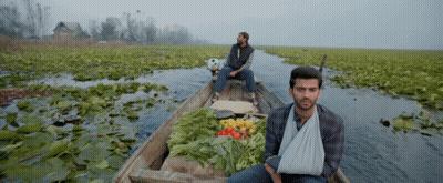 Man With Bandage On Arm Sits In Boat With Vegetables GIF