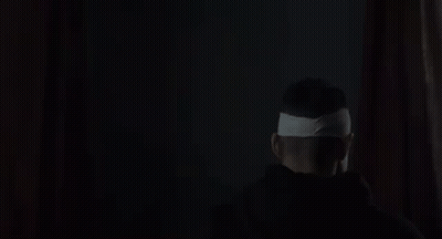 Man With Bandage On Head Smiling In Dark GIF