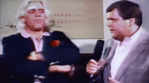 Man With Bandage Talking To Man With Microphone GIF