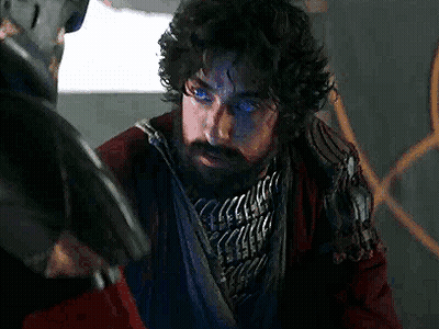 Man With Beard And Blue Eyes Next To Man Holding Gun GIF