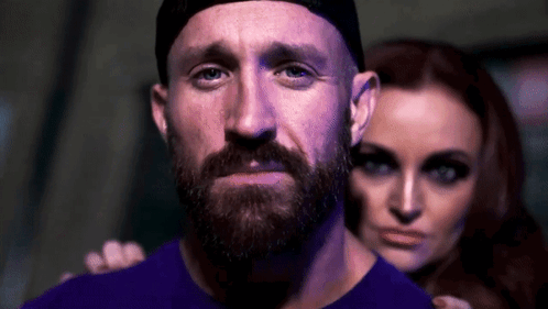 Man With Beard And Hat Standing Next To Woman In Dark Room GIF