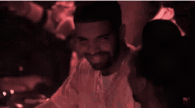 Man With Beard And Necklace Smiles In Dark Room GIF
