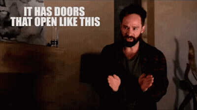 Man With Beard And Sign Saying It Has Doors That Open Like This GIF